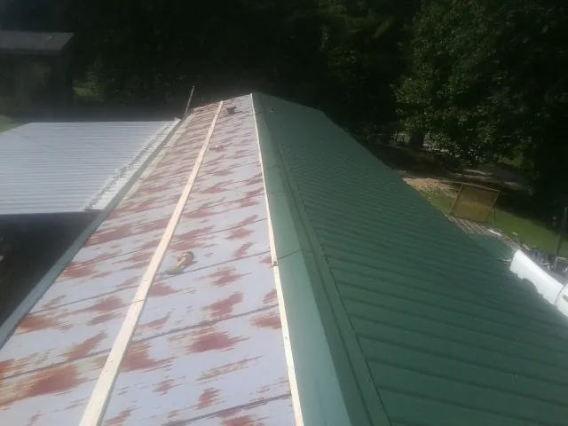 Old rusted panels beside newly installed green metal roofing — Wind Damage Roof Repair by Roofing Brothers in Edinburg