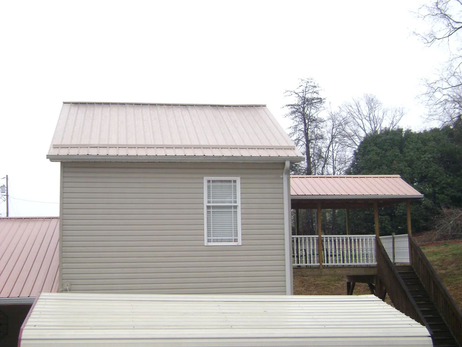 Tan metal roofs on a two story addition and attached porch, from a Roof Replacement job in Edinburg