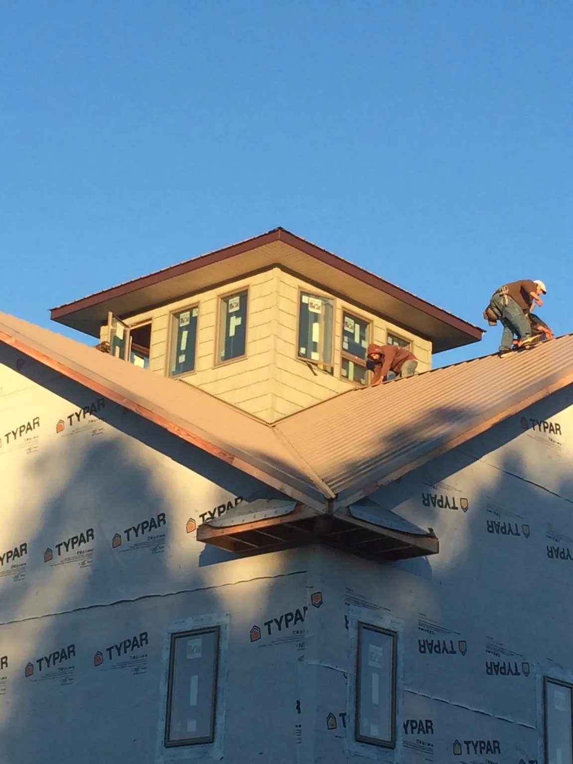 Roofers working around a rooftop cupola on a new metal roof at sunset — Roof Waterproofing in Edinburg by Roofing Brothers